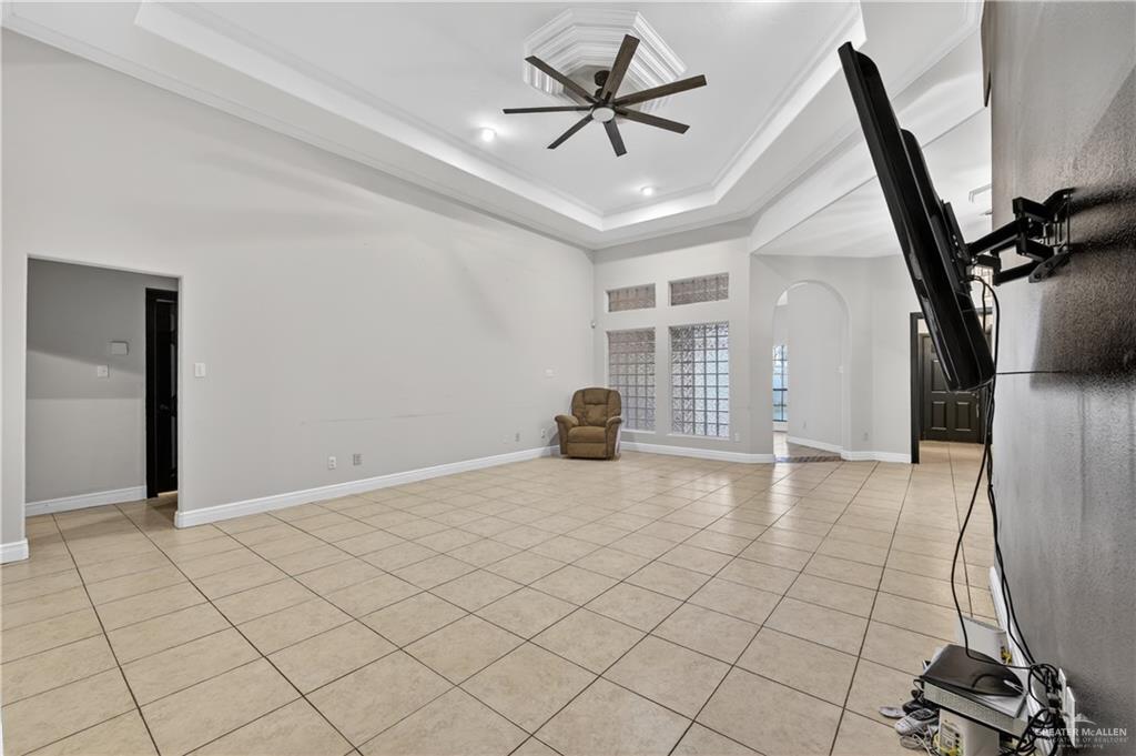 6004 North Cynthia Street McAllen, TX 78504 - Photo 5 of 25 Spacious living area featuring large format tile flooring, a tray ceiling with crown molding, and a ceiling fan