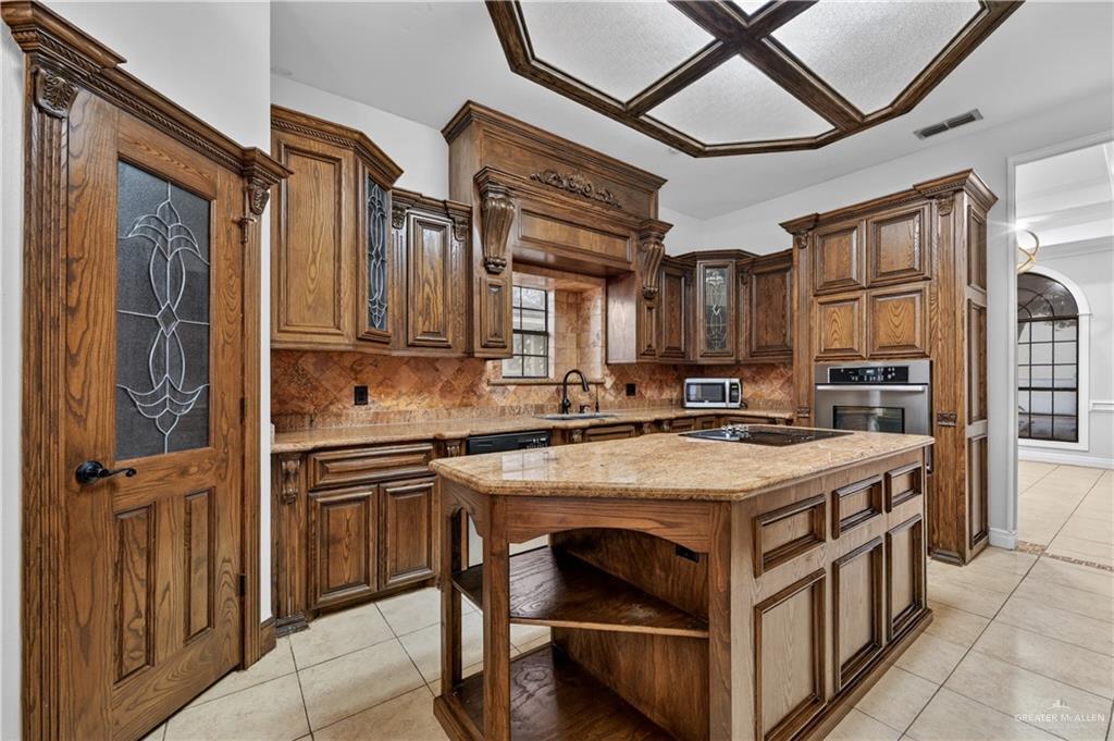 6004 North Cynthia Street McAllen, TX 78504 - Photo 8 of 25 Kitchen featuring wood cabinetry, granite countertops, tile flooring, a coffered ceiling, and a built-in oven