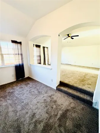 an empty room with chandelier fan and windows