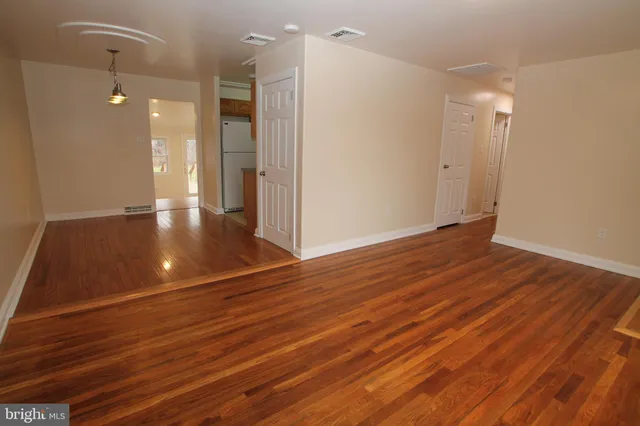 a view of an empty room with wooden floor and a bathroom
