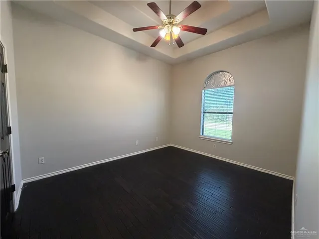 an empty room with wooden floor chandelier fan and windows