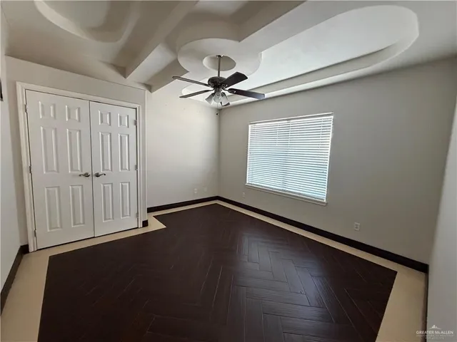 an empty room with wooden floor ceiling fan and windows