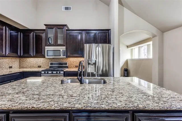 a kitchen with stainless steel appliances granite countertop a refrigerator and a stove top oven