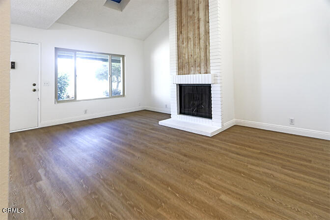3224 Sunset Lane Oxnard, CA 93035 - Photo 9 of 20 an empty room with wooden floor fireplace and windows