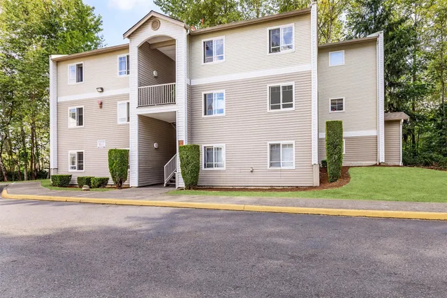 a view of a house with a yard and large tree