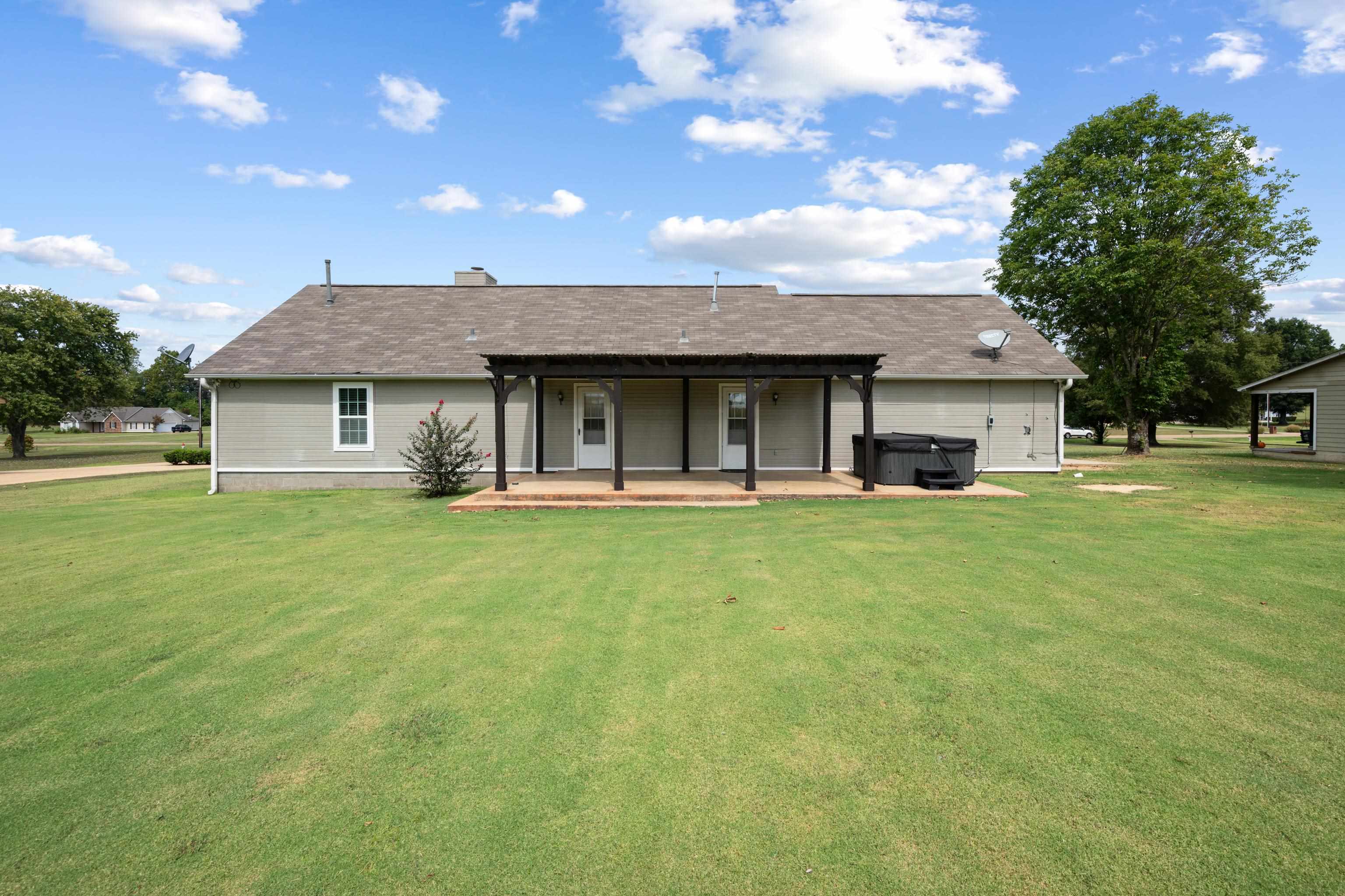225 Brierhedge Road Covington, TN 38019 - Photo 32 of 34 Back of property with a hot tub, a lawn, a patio, a chimney, and a shingled roof