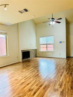 a view of empty room with wooden floor and fan