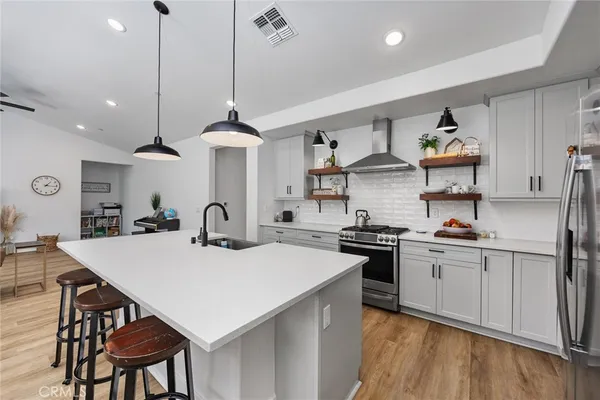 a kitchen with stainless steel appliances granite countertop a stove a sink dishwasher and a refrigerator with wooden floor