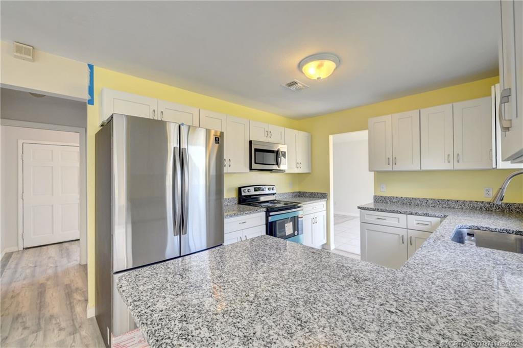 297 Southwest Homeland Road Port St. Lucie, FL 34953 - Photo 12 of 32 a kitchen with a refrigerator sink and stove