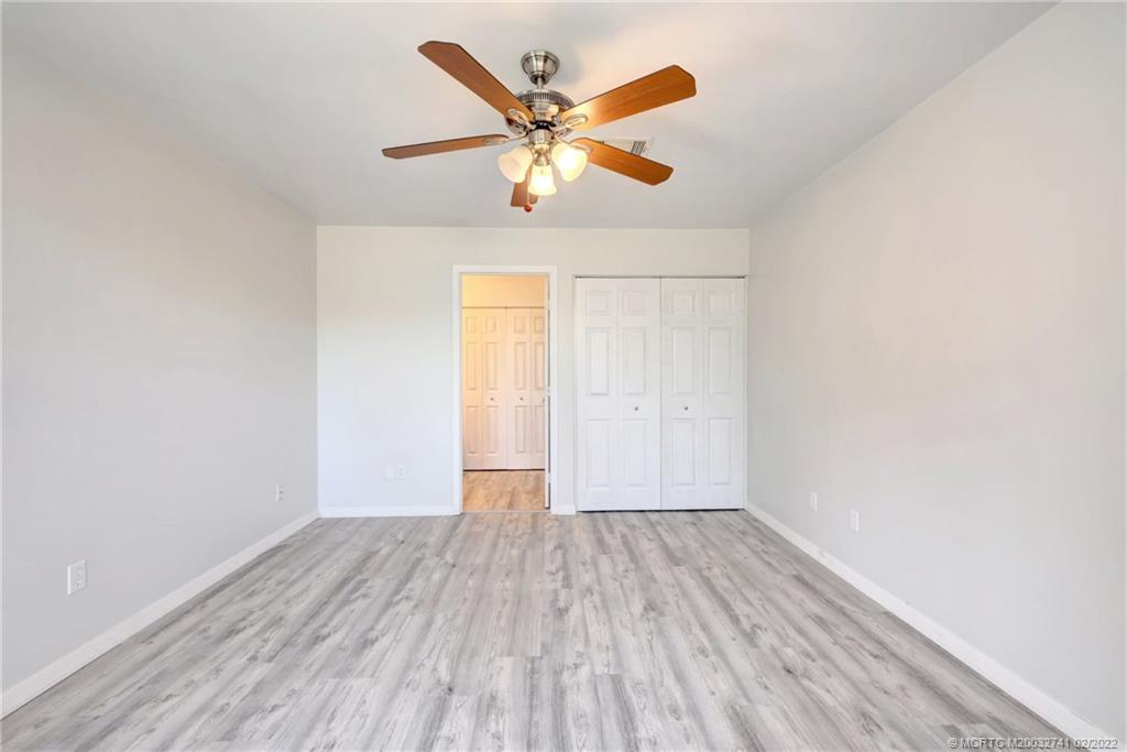 297 Southwest Homeland Road Port St. Lucie, FL 34953 - Photo 17 of 32 an empty room with wooden floor and ceiling fan