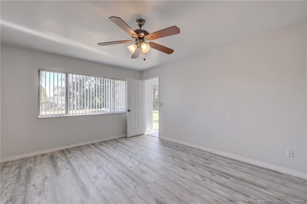 297 Southwest Homeland Road Port St. Lucie, FL 34953 - Photo 18 of 32 an empty room with wooden floor fan and windows