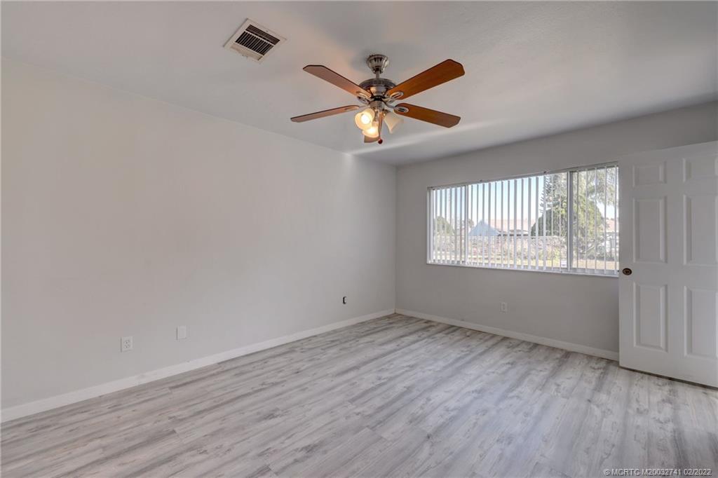297 Southwest Homeland Road Port St. Lucie, FL 34953 - Photo 19 of 32 a view of an empty room with wooden floor and a window