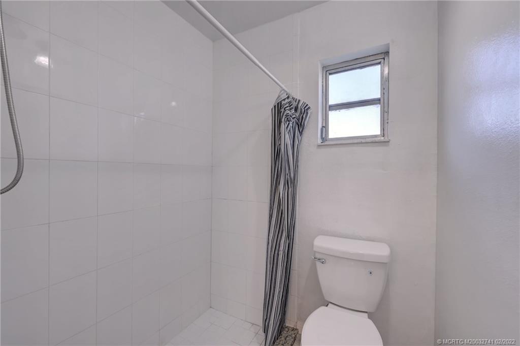 297 Southwest Homeland Road Port St. Lucie, FL 34953 - Photo 22 of 32 a white toilet sitting next to a bathroom sink and vanity
