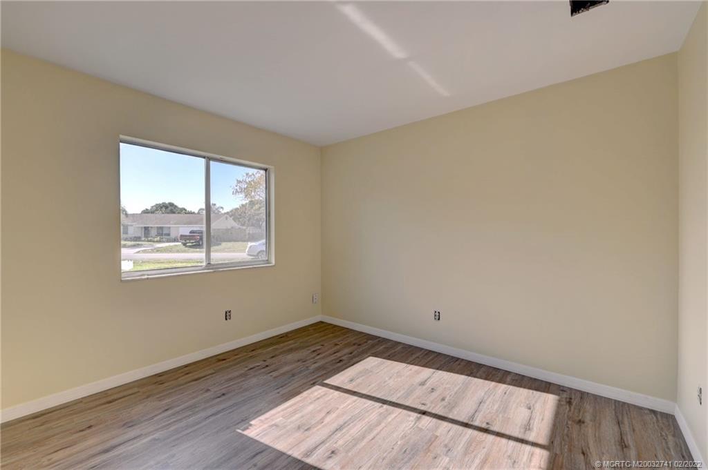 297 Southwest Homeland Road Port St. Lucie, FL 34953 - Photo 25 of 32 an empty room with wooden floor and windows
