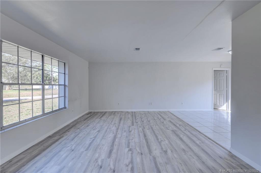 297 Southwest Homeland Road Port St. Lucie, FL 34953 - Photo 3 of 32 wooden floor in an empty room with a window