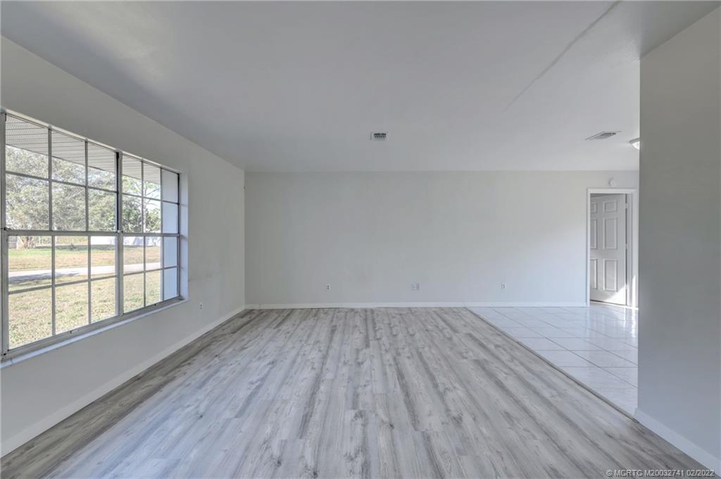 297 Southwest Homeland Road Port St. Lucie, FL 34953 - Photo 4 of 32 wooden floor in an empty room with a window
