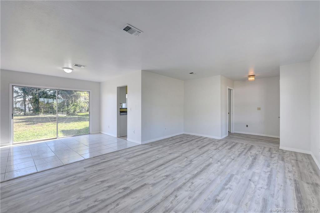 297 Southwest Homeland Road Port St. Lucie, FL 34953 - Photo 5 of 32 a view of an empty room with wooden floor and a window
