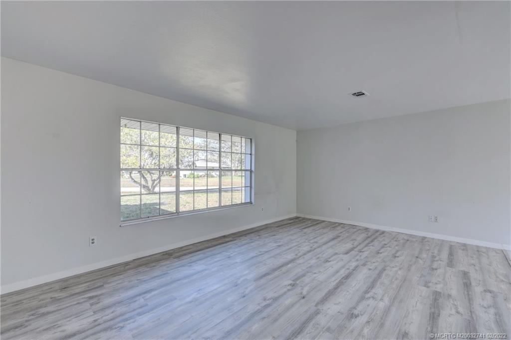 297 Southwest Homeland Road Port St. Lucie, FL 34953 - Photo 6 of 32 an empty room with wooden floor and windows