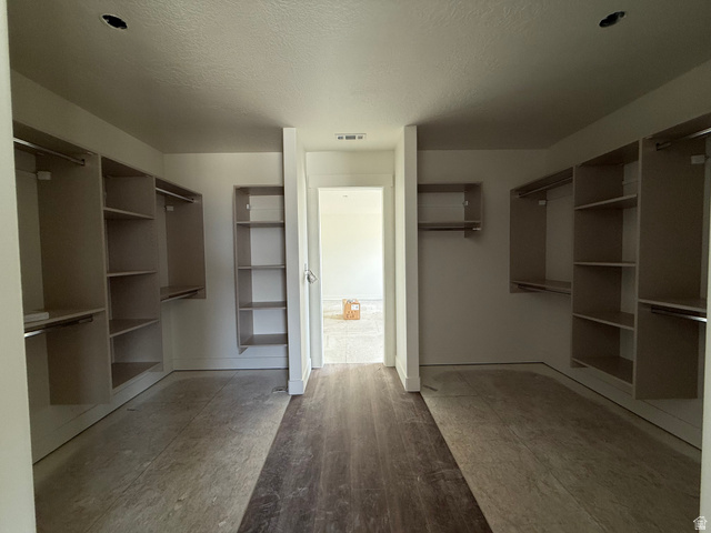 1008 West 3410 South Nibley, UT 84321 - Photo 12 of 26 Spacious walk-in closet featuring multiple shelving units and hanging rods, wood-finish flooring, and a neutral wall palette
