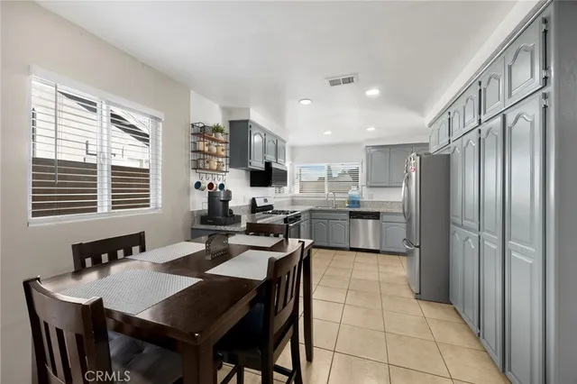a kitchen with stainless steel appliances granite countertop a sink dishwasher a stove a refrigerator a dining table and chairs with wooden floor