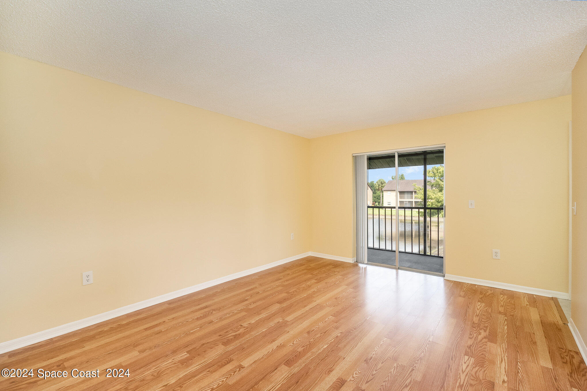 280 Spring Drive, Unit 8 Merritt Island, FL 32953 - Photo 5 of 26 a view of an empty room with wooden floor and a window