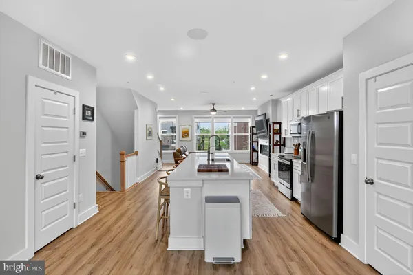 a view of a kitchen with kitchen island stainless steel appliances refrigerator stove microwave and cabinets