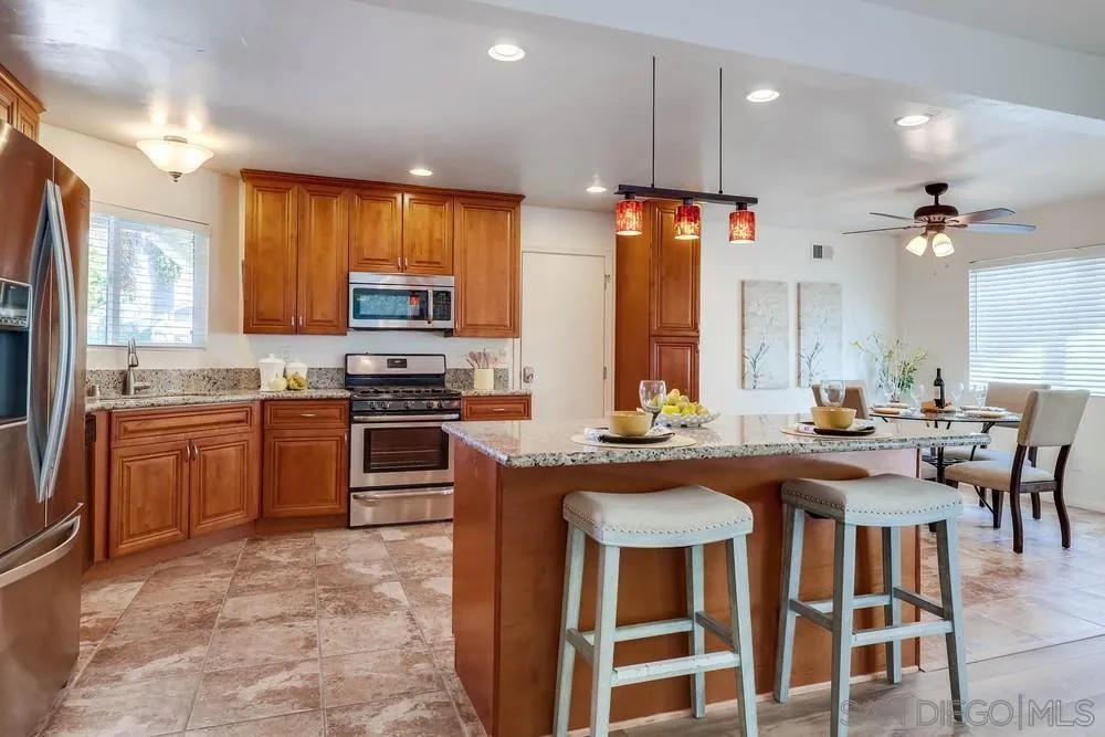 12711 Rios Road San Diego, CA 92128 - Photo 14 of 33 a kitchen with a stove a sink a dining table and chairs