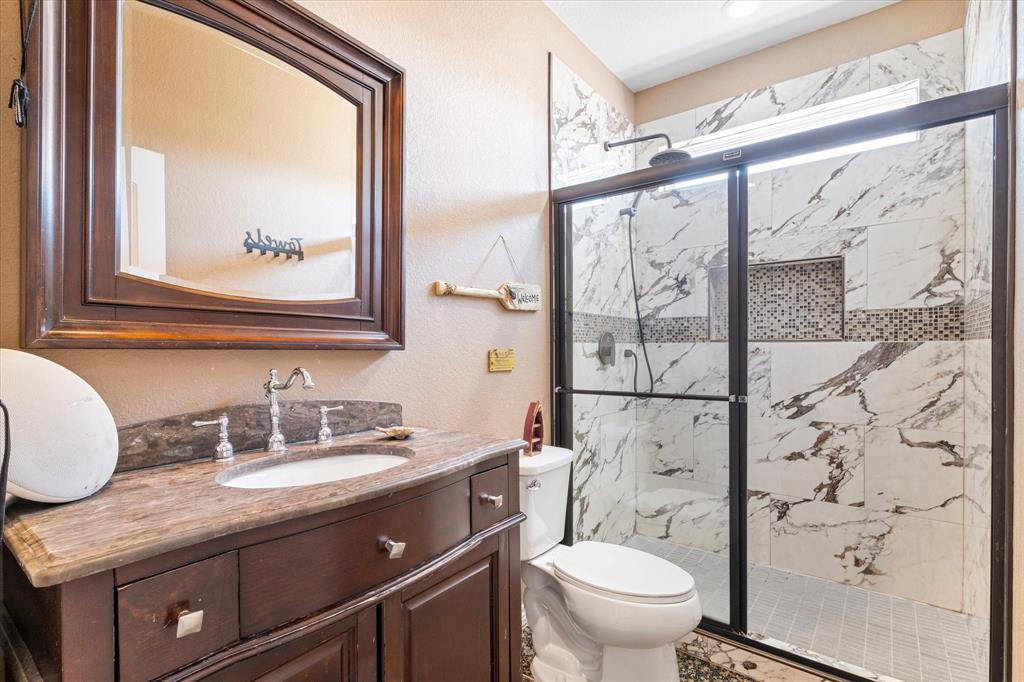 2885 Enloe Road Howe, TX 75459 - Photo 28 of 39 a bathroom with a granite countertop sink a toilet and a mirror