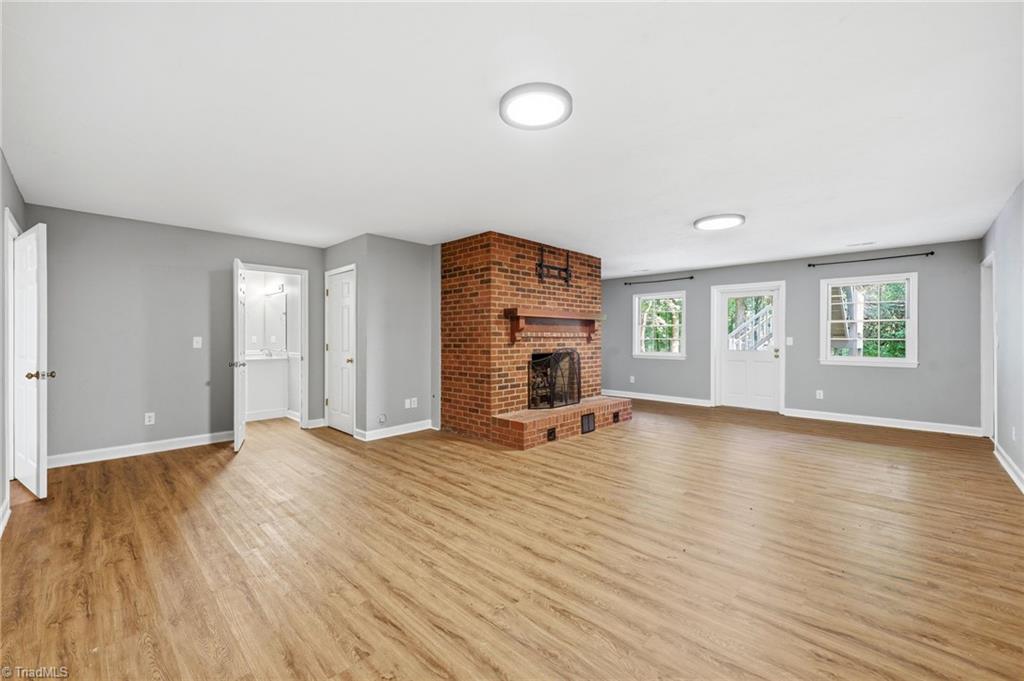 8861 Boylston Road Colfax, NC 27235 - Photo 34 of 50 Spacious walk-out lower level featuring a fireplace, private exterior entrance, guest bedroom, full bath, and additional flex room—ideal for multi-generational living, an in-law suite, guests, recreation, or a home office.