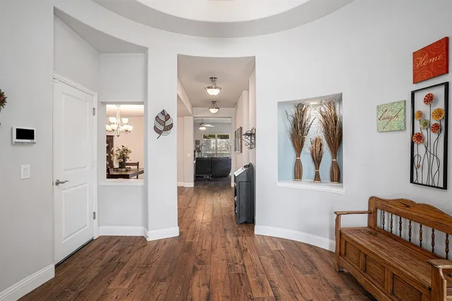 a view of a hallway to a livingroom with wooden floor and furniture