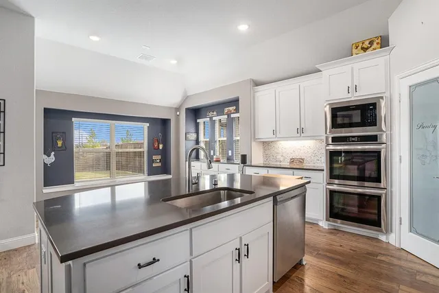 a kitchen with stainless steel appliances granite countertop a sink a stove and a refrigerator