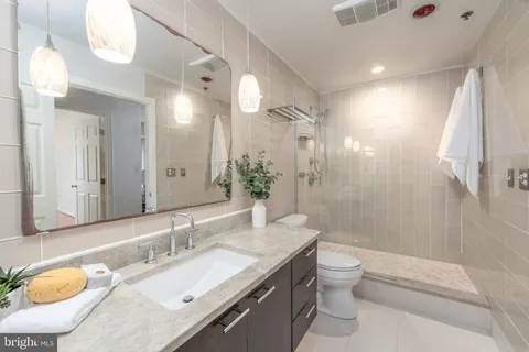 a bathroom with a granite countertop sink toilet a large mirror a shower and bathtub