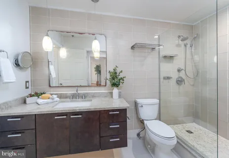 a bathroom with a granite countertop sink toilet a mirror and shower
