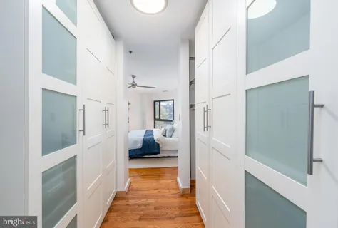 a hallway with white cabinets and wooden floor
