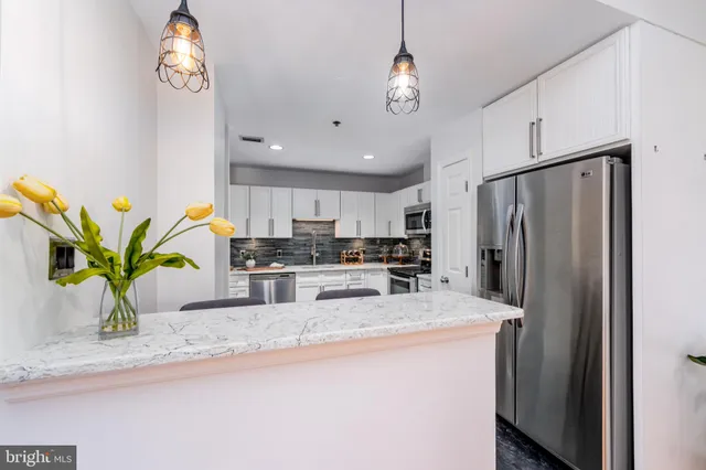 a kitchen with stainless steel appliances granite countertop a refrigerator a sink a stove and cabinets