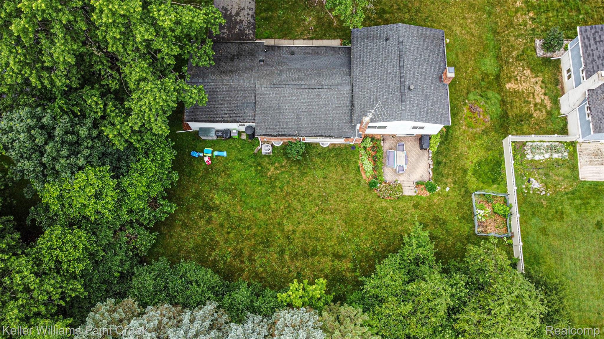 7093 Stonebrook Road West Bloomfield, MI 48322 - Photo 63 of 64 Expansive rear yard featuring mature perimeter trees, a lush green lawn, and a stone patio