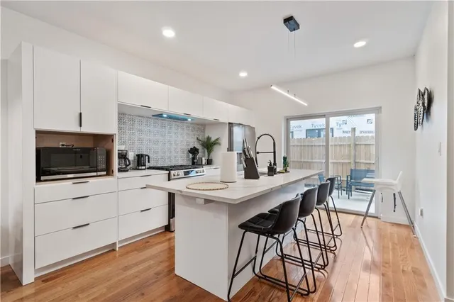 a kitchen with stainless steel appliances a kitchen island hardwood floor sink stove dining table and chairs
