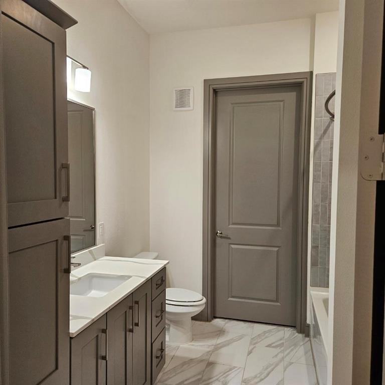 2700 Old Denton Road, Unit 2238 Carrollton, TX 75007 - Photo 18 of 21 Modern bathroom featuring a single vanity with stone-finish countertop, wood-finish cabinetry, and an integrated rectangular sink
