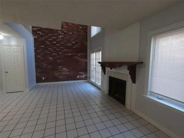 a view of an empty room with a fireplace and window