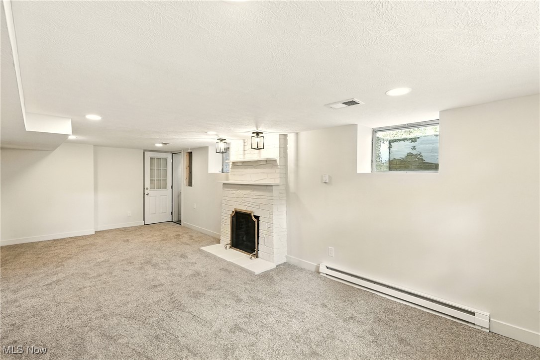 2844 Kent Road Stow, OH 44224 - Photo 34 of 47 Below grade area featuring a baseboard heating unit, a fireplace with flush hearth, a textured ceiling, carpet floors, and recessed lighting