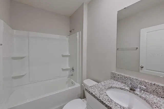 a bathroom with a granite countertop sink a toilet and shower