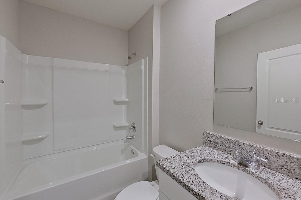 32044 Katelin Circle Leesburg, FL 34748 - Photo 13 of 20 a bathroom with a granite countertop sink a toilet and shower