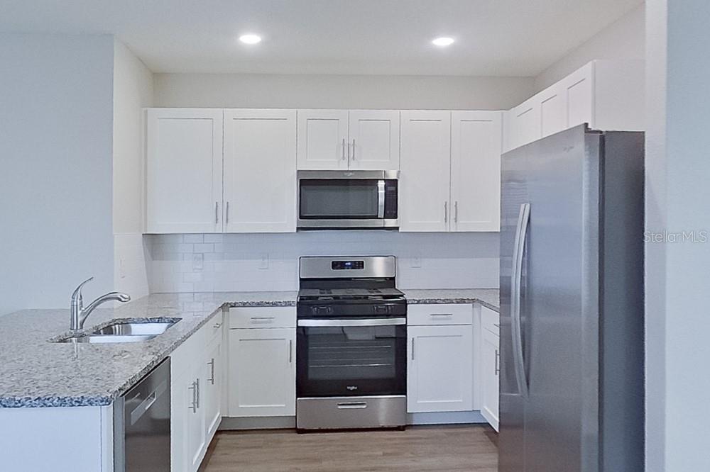 32044 Katelin Circle Leesburg, FL 34748 - Photo 5 of 20 a kitchen with white cabinets and stainless steel appliances