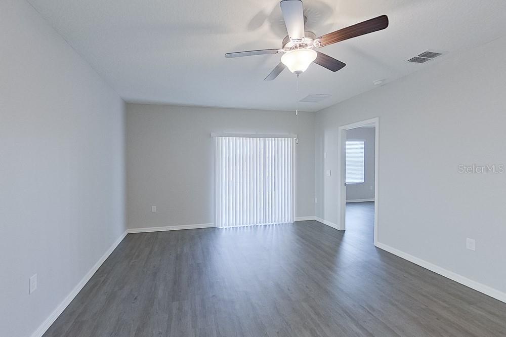 32044 Katelin Circle Leesburg, FL 34748 - Photo 7 of 20 an empty room with wooden floor ceiling fan and window