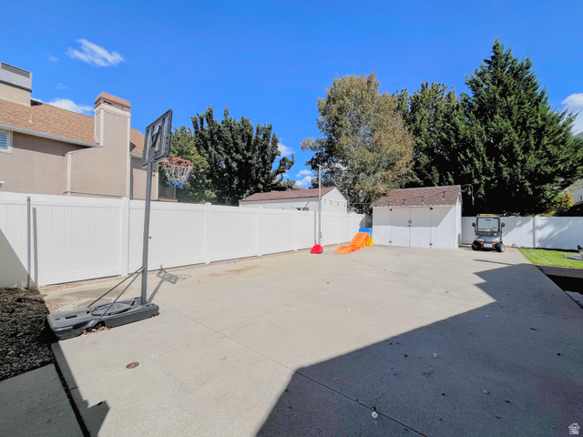 12169 Hidden Valley Road, Unit 44 Sandy, UT 84092 - Photo 45 of 49 Expansive concrete patio with white privacy fencing, two storage sheds, and mature perimeter trees