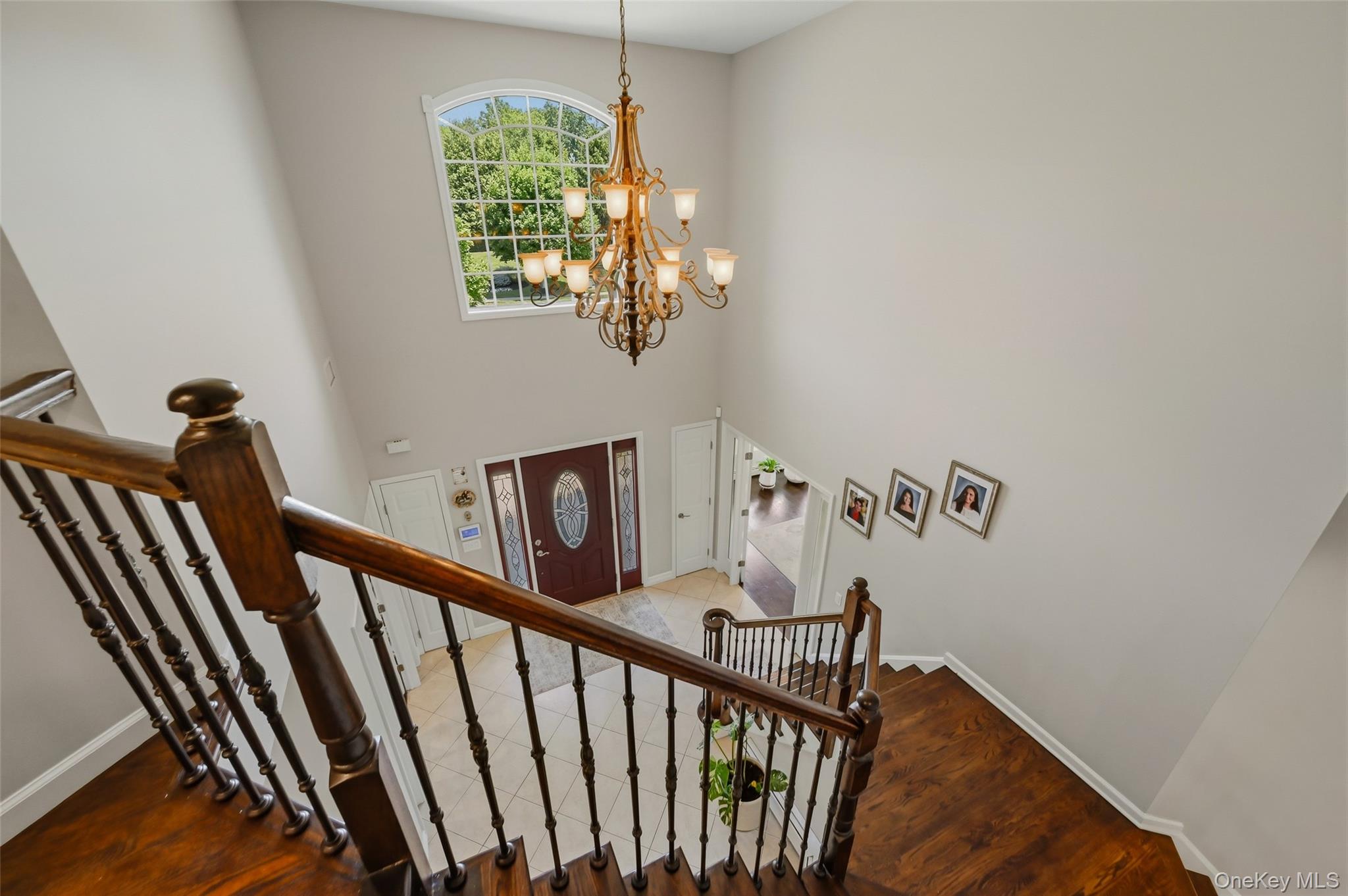 51 Meriwether Trail Congers, NY 10920 - Photo 20 of 50 Two-story foyer featuring an arched transom window, a multi-tier chandelier, and a wood-finish staircase with wrought iron balusters