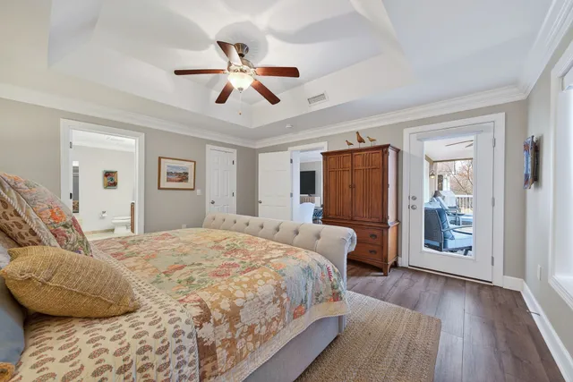 a bedroom with a bed ceiling fan and a wooden floor