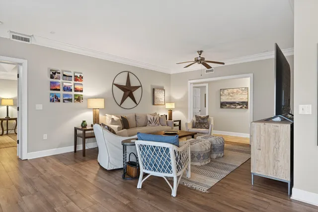 a living room with furniture a large window and wooden floor
