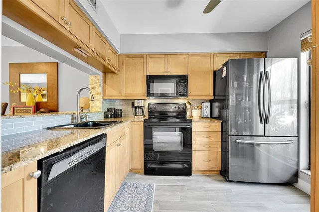 a kitchen with stainless steel appliances granite countertop a refrigerator a stove and a sink with wooden floor