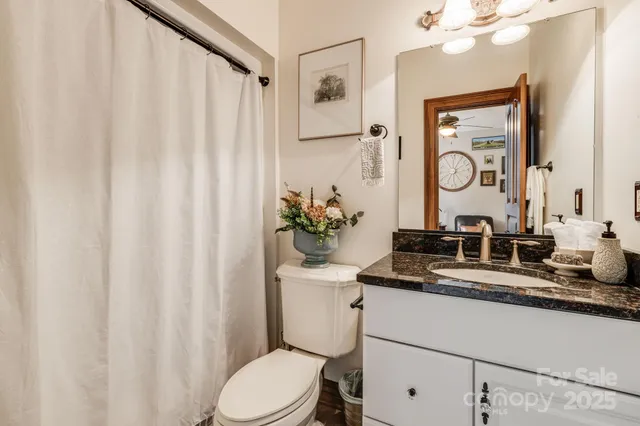 a bathroom with a granite countertop sink mirror vanity and toilet